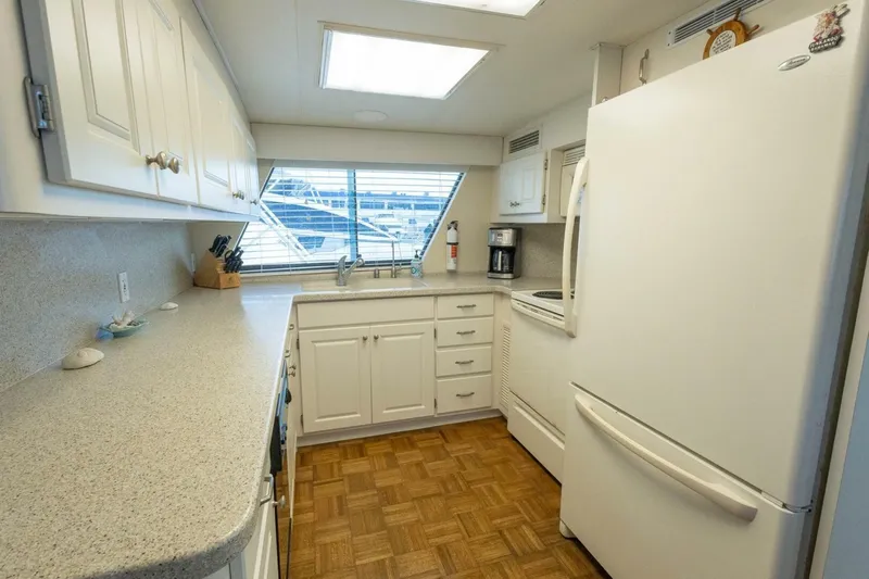  Yacht Photos Pics Kitchen interior of 1987 Hatteras 70 Cockpit Motor Yacht with white cabinetry and appliances.