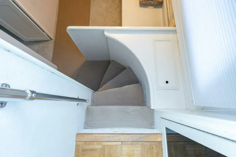  Yacht Photos Pics Staircase inside 1987 Hatteras 70 Cockpit Motor Yacht, featuring curved steps and metal railing.
