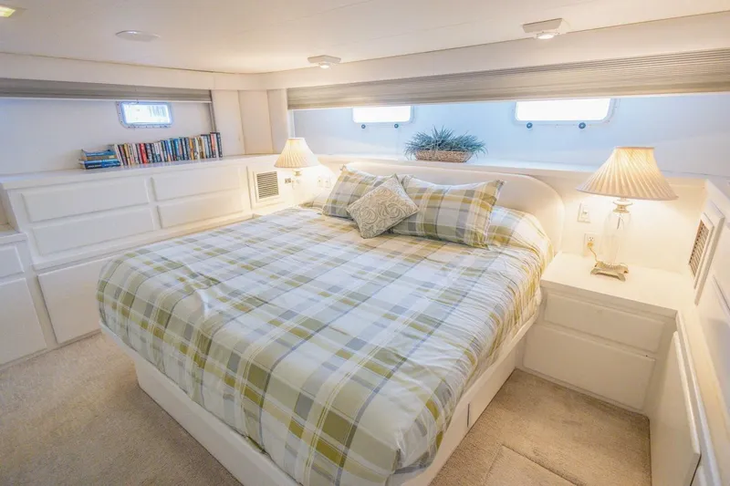  Yacht Photos Pics Luxurious bedroom in 1987 Hatteras 70 Cockpit Motor Yacht with plaid bedding and elegant decor.