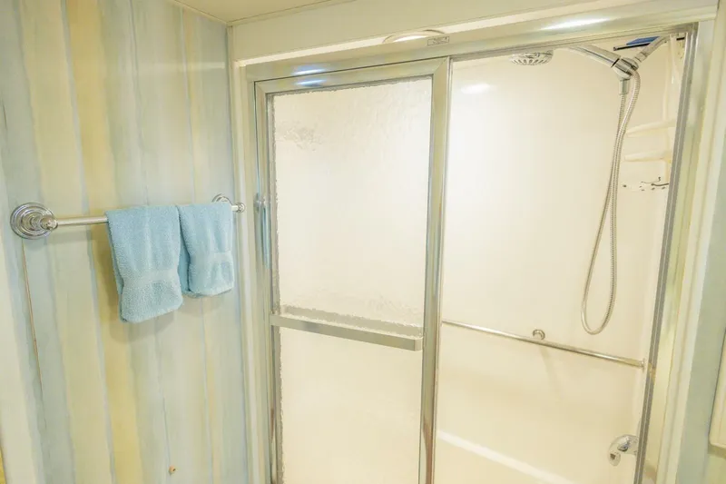  Yacht Photos Pics Bathroom with glass shower door and blue towels on a 1987 Hatteras 70 Cockpit Motor Yacht.