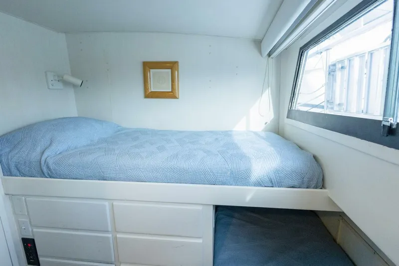  Yacht Photos Pics Cozy cabin bed in 1987 Hatteras 70 Cockpit Motor Yacht with blue bedding and window.