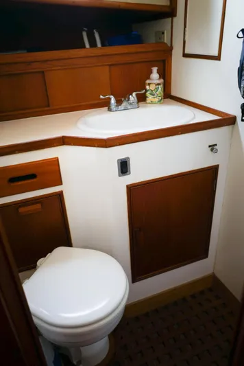  Yacht Photos Pics 1986 Grand Banks 36 Classic boat bathroom with sink and toilet, featuring wooden cabinetry.