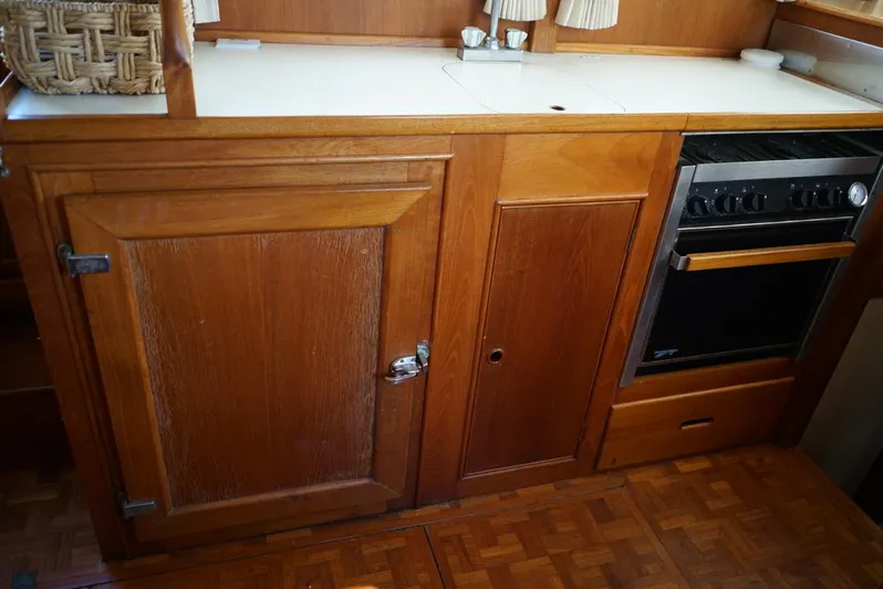  Yacht Photos Pics Wooden kitchen area in a 1986 Grand Banks 36 Classic boat, featuring cabinets and a stove.