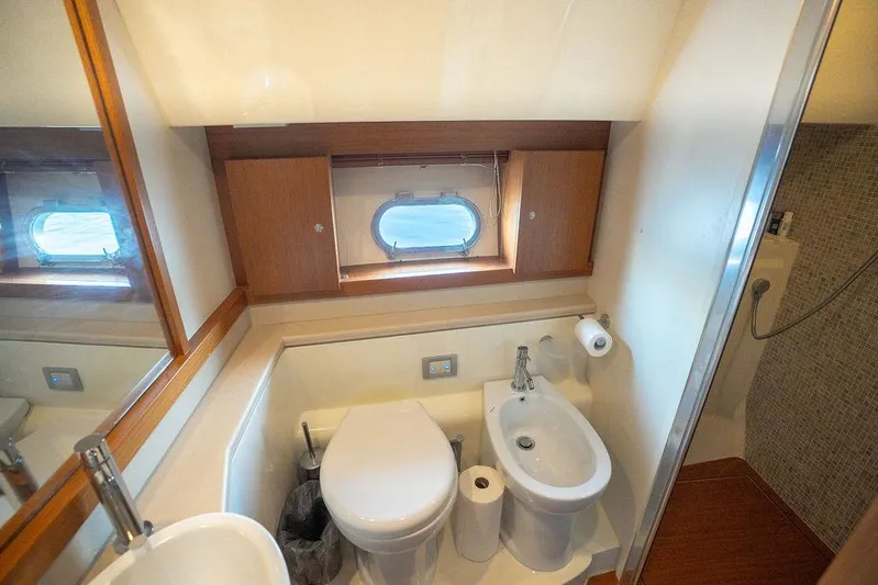  Yacht Photos Pics Bathroom interior of 2009 Ferretti Yachts 470, featuring toilet, bidet, and porthole window.