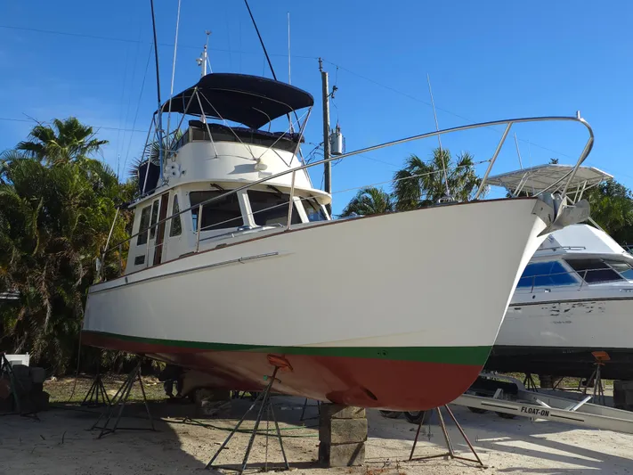 Lindy Yacht Photos Pics 2004 Legacy Sedan Flybridge boat on stands, surrounded by palm trees and clear blue sky.