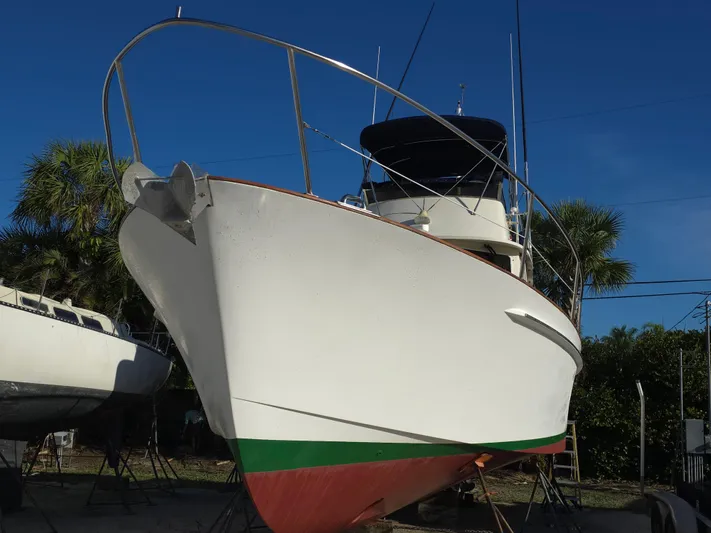 Lindy Yacht Photos Pics 2004 Legacy Sedan Flybridge boat on land, blue sky background, palm trees nearby.