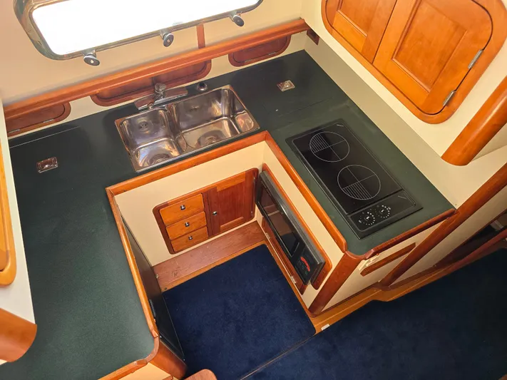 Lindy Yacht Photos Pics 2004 Legacy Sedan Flybridge kitchen with dual sinks, stovetop, and wooden cabinetry.