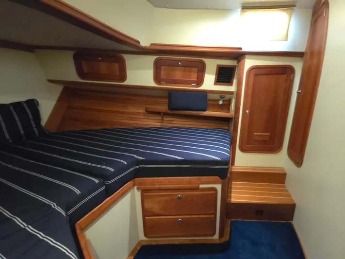 Lindy Yacht Photos Pics 2004 Legacy Sedan Flybridge cabin with striped bedding, wooden storage, and cozy interior design.