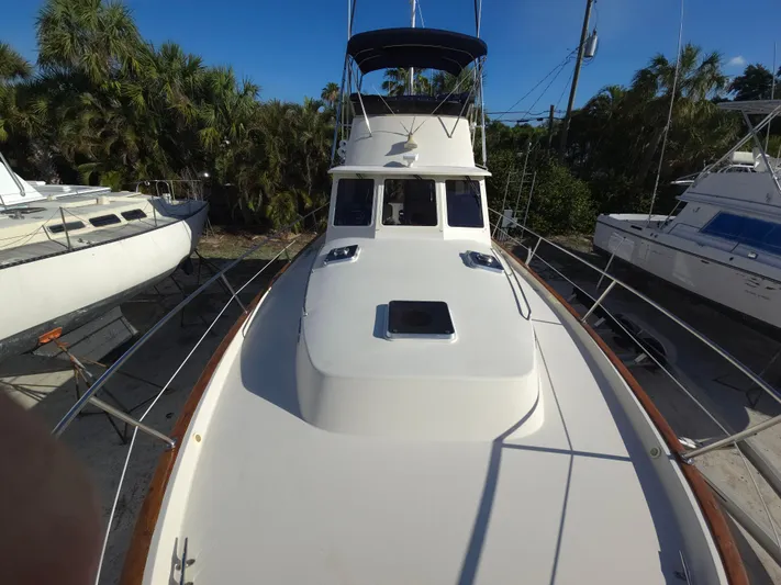 Lindy Yacht Photos Pics 2004 Legacy Sedan Flybridge boat docked, surrounded by trees and other vessels.