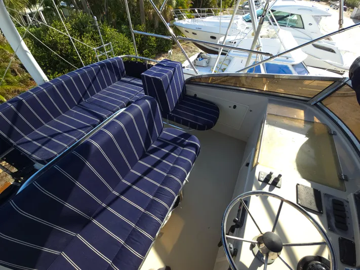 Lindy Yacht Photos Pics 2004 Legacy Sedan Flybridge with striped seating and steering wheel, docked near other boats.