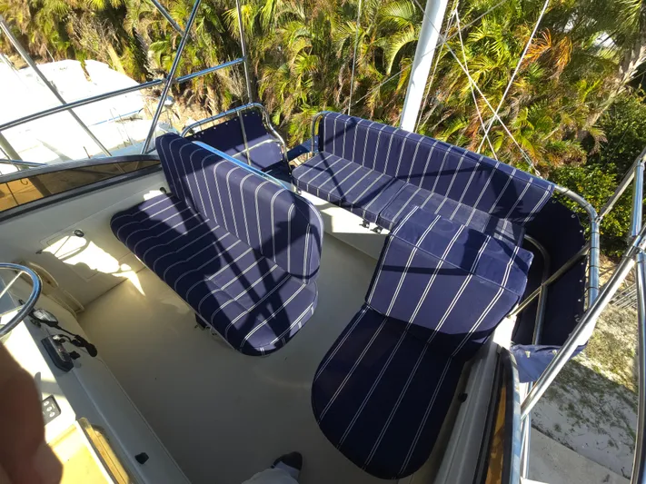 Lindy Yacht Photos Pics 2004 Legacy Sedan Flybridge with blue striped seating, surrounded by lush greenery.