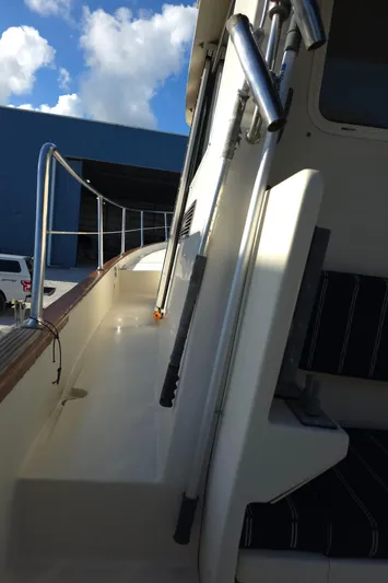 Lindy Yacht Photos Pics 2004 Legacy Sedan Flybridge boat with sleek railing and cushioned seating under a blue sky.