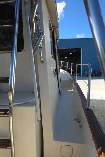 Lindy Yacht Photos Pics 2004 Legacy Sedan Flybridge yacht, side view with railing, near a blue warehouse.