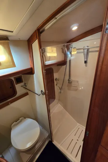 Lindy Yacht Photos Pics 2004 Legacy Sedan Flybridge bathroom with shower, wooden accents, and compact design.