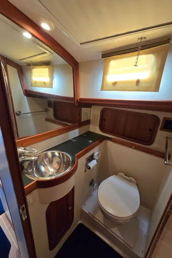 Lindy Yacht Photos Pics 2004 Legacy Sedan Flybridge bathroom with sink, toilet, and wooden accents.