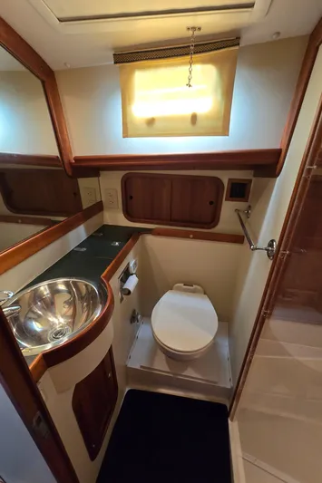 Lindy Yacht Photos Pics 2004 Legacy Sedan Flybridge bathroom with sink, toilet, and wooden accents.