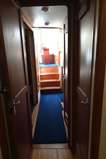 Lindy Yacht Photos Pics Interior hallway of 2004 Legacy Sedan Flybridge with wooden doors and blue carpet.