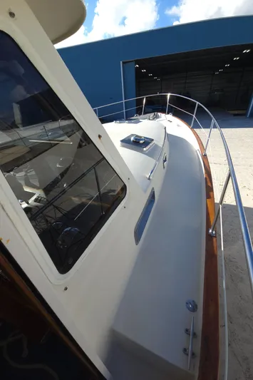 Lindy Yacht Photos Pics 2004 Legacy Sedan Flybridge boat docked near a blue warehouse under a clear sky.