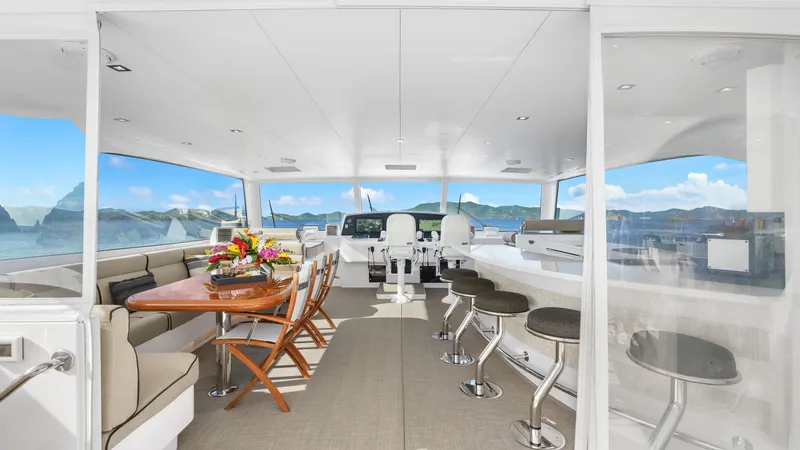 Sea Glass Yacht Photos Pics Luxurious interior of 2018 Horizon PC74 yacht with seating, table, and bar stools.