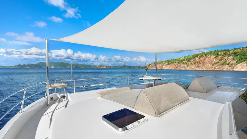 Sea Glass Yacht Photos Pics Luxurious Horizon PC74 yacht deck with sunshade, overlooking serene ocean and lush coastline.