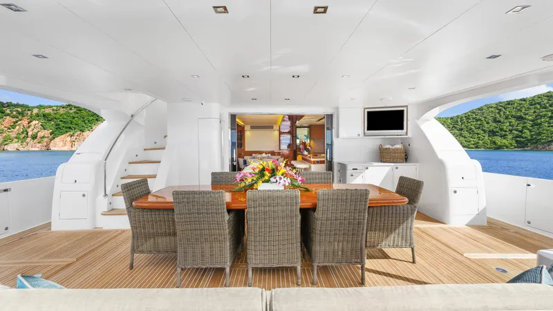 Sea Glass Yacht Photos Pics Luxurious Horizon PC74 yacht deck with dining area, wicker chairs, and ocean view, 2018 model.
