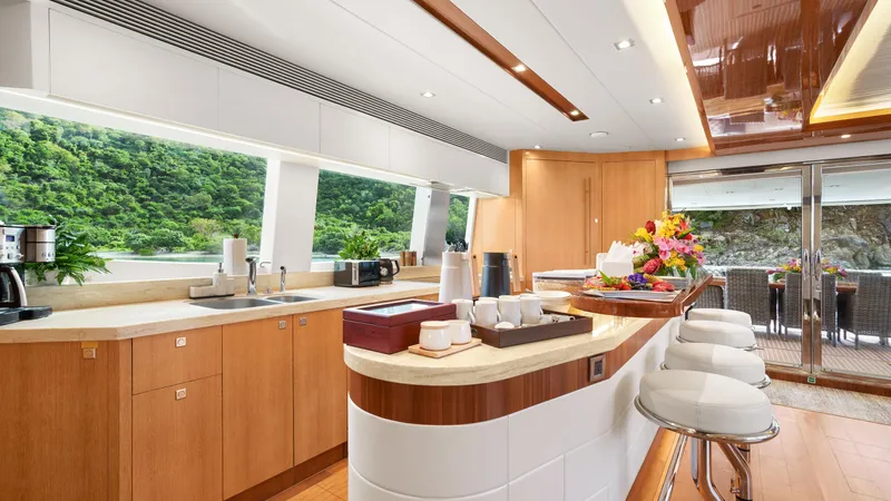 Sea Glass Yacht Photos Pics Luxurious yacht kitchen interior with modern design, featuring wooden cabinetry and scenic window views.