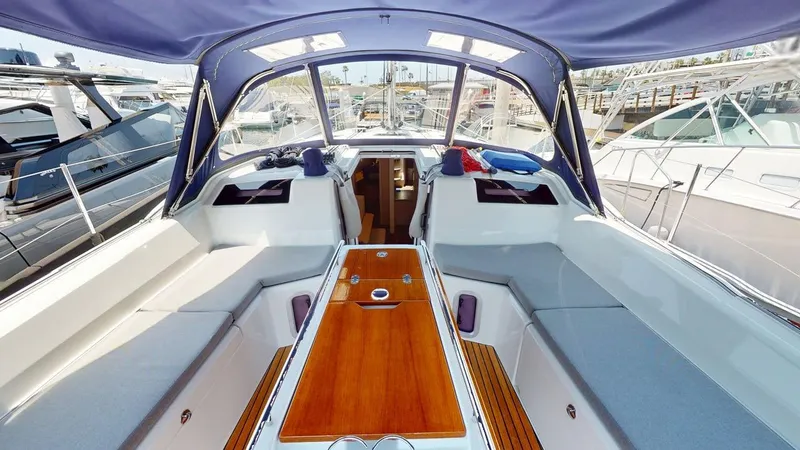 Evelyn Yacht Photos Pics 2021 Beneteau Oceanis 40.1 yacht cockpit with wooden table and cushioned seating.