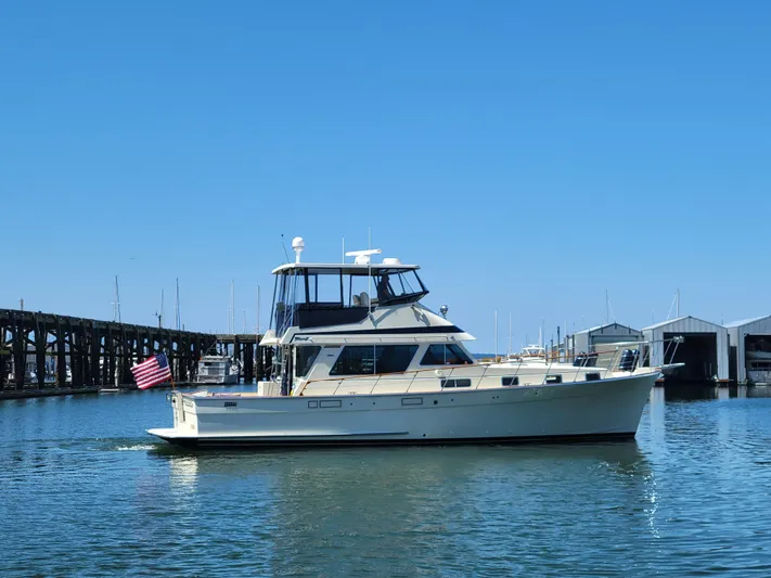 No Agenda Yacht Photos Pics 1982 Tollycraft 48' Sedan yacht cruising in a marina under clear blue skies.