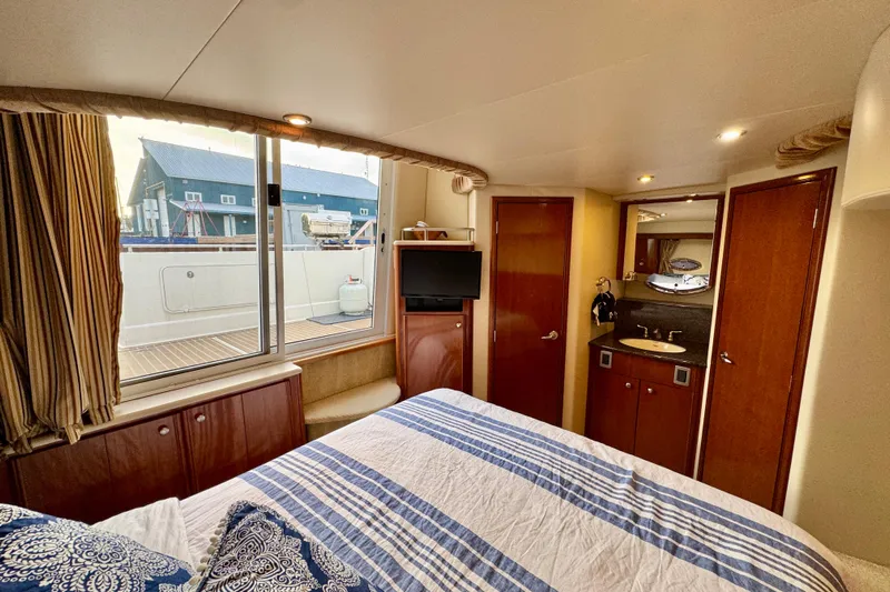 Shake N' Bake Yacht Photos Pics Luxurious 2006 Meridian Motoryacht bedroom with striped bedding, TV, and ensuite bathroom.