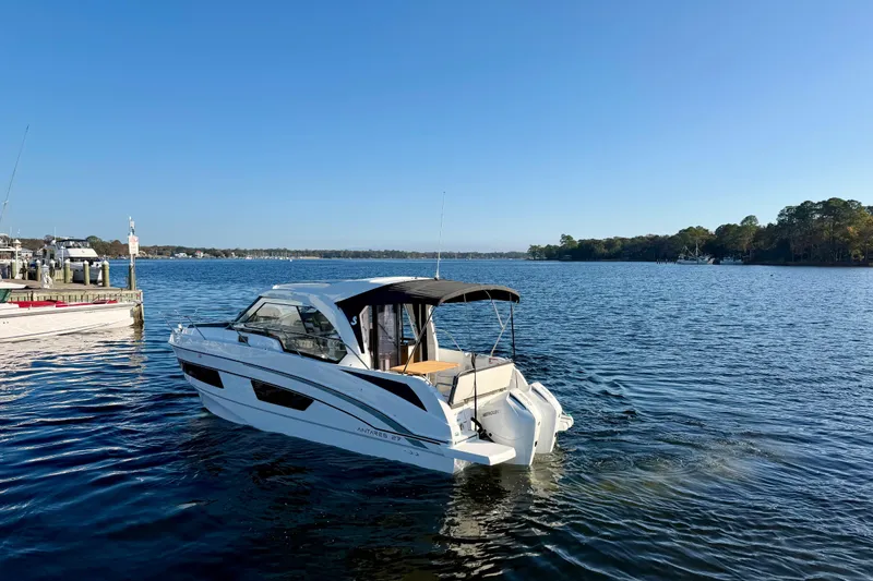  Yacht Photos Pics 2021 Beneteau Antares 9 motorboat cruising on a serene lake under a clear blue sky.