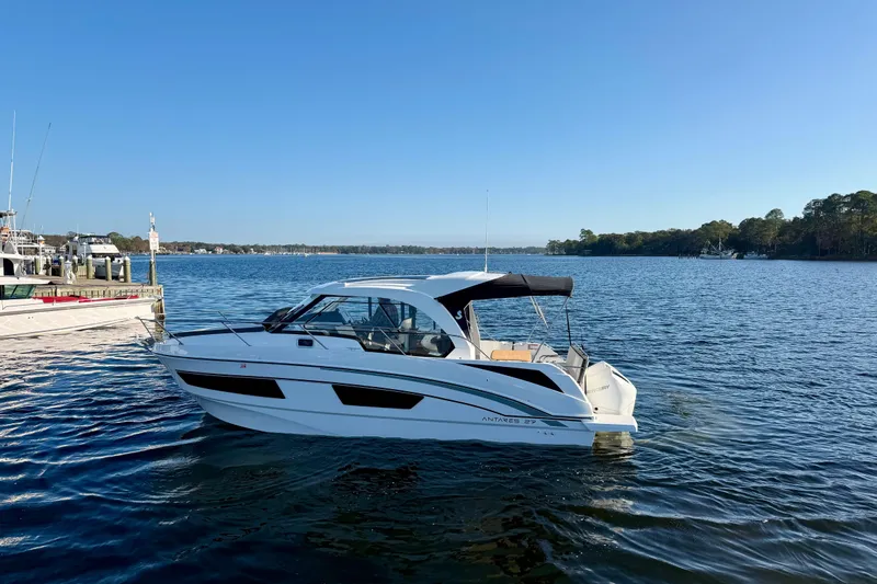  Yacht Photos Pics 2021 Beneteau Antares 9 boat on a calm lake under clear blue sky.