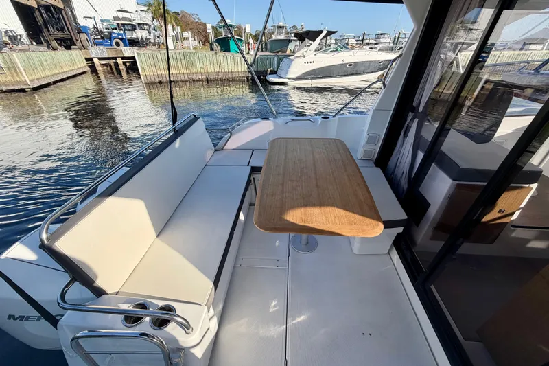  Yacht Photos Pics 2021 Beneteau Antares 9 boat interior with seating and wooden table by the dock.