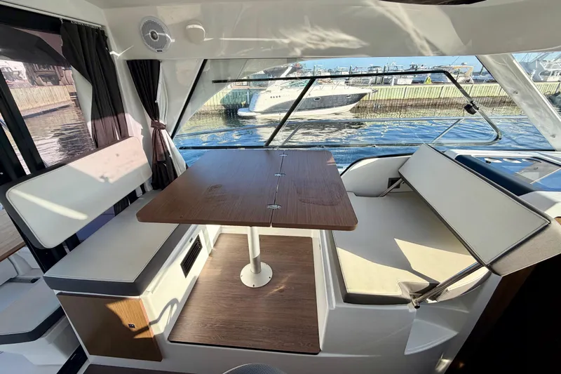  Yacht Photos Pics Interior of 2021 Beneteau Antares 9 boat with seating and table, dockside view.