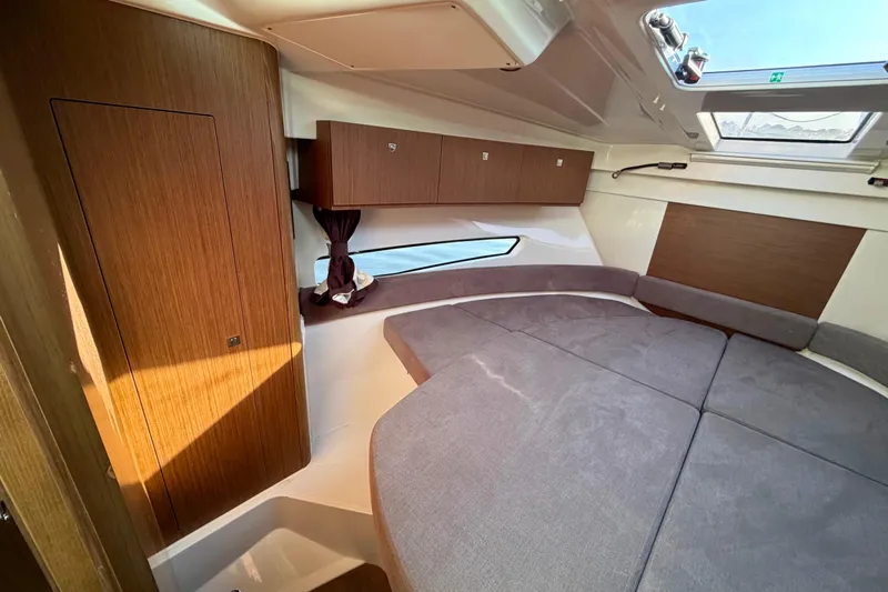  Yacht Photos Pics 2021 Beneteau Antares 9 cabin interior with wood paneling and gray upholstery.