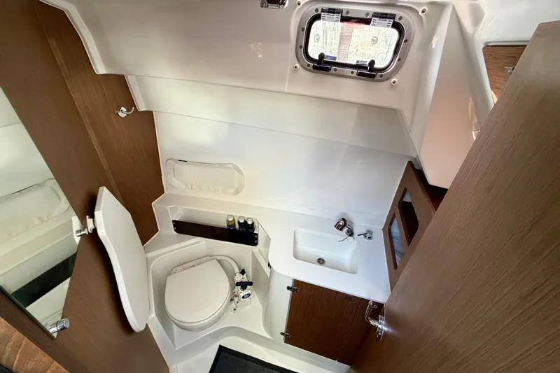  Yacht Photos Pics 2021 Beneteau Antares 9 bathroom interior with toilet, sink, and wooden cabinetry.