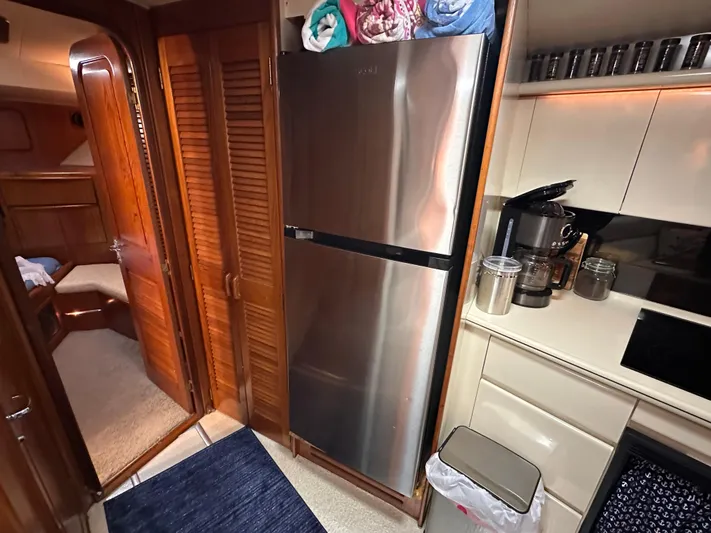 Sea Suite Yacht Photos Pics 1989 Viking 44 Motor Yacht kitchen with stainless steel fridge, coffee maker, and wooden cabinetry.