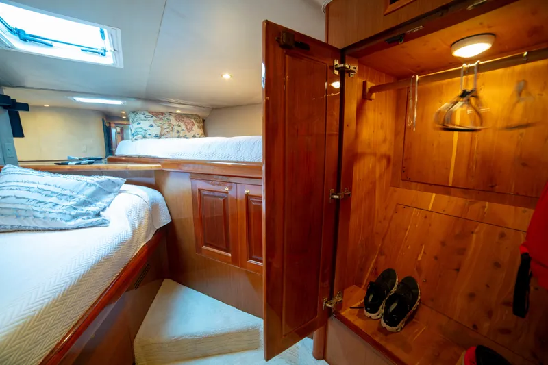 Prime Time Yacht Photos Pics Luxurious cabin interior of 2002 Viking 65 Enclosed Bridge yacht with cozy bedding and wooden closet.