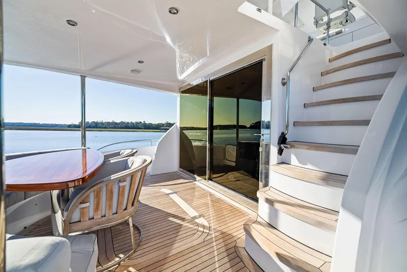 Bonefish Yacht Photos Pics Luxurious 2016 Hatteras M60 yacht deck with seating and staircase, overlooking serene waters.