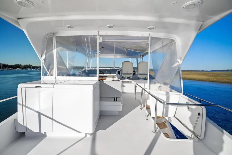 Bonefish Yacht Photos Pics 2016 Hatteras M60 yacht deck with seating, overlooking serene water and clear skies.