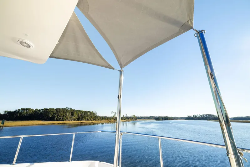 Bonefish Yacht Photos Pics Hatteras M60 yacht view, 2016 model, overlooking serene water and distant shoreline.