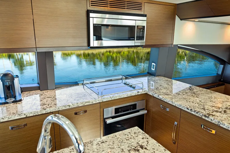 Bonefish Yacht Photos Pics Luxurious kitchen interior of 2016 Hatteras M60 yacht with granite countertops and scenic window view.