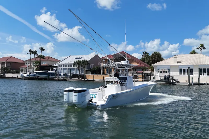 Cherokee Yacht Photos Pics 2022 Ocean Runner 29 Center Console boat cruising near waterfront homes under a clear blue sky.