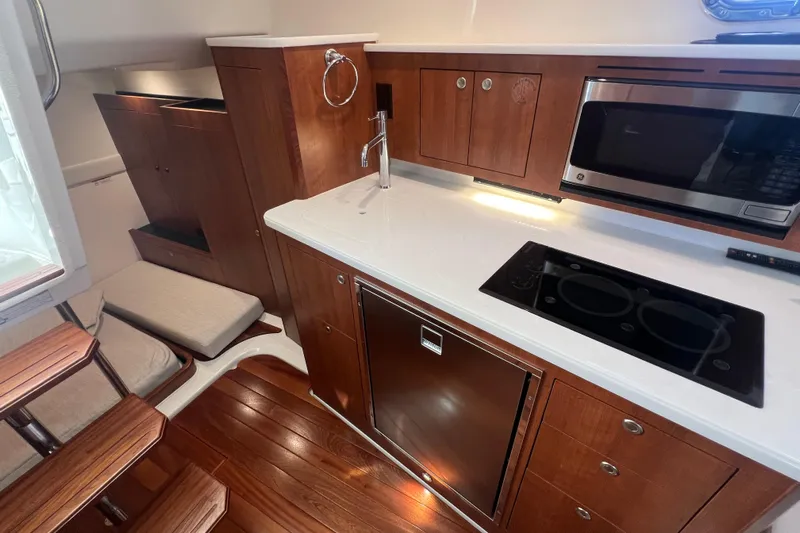 Seaquel Yacht Photos Pics Luxurious 2026 Pursuit OS 355 Offshore yacht kitchen with wood cabinetry and modern appliances.