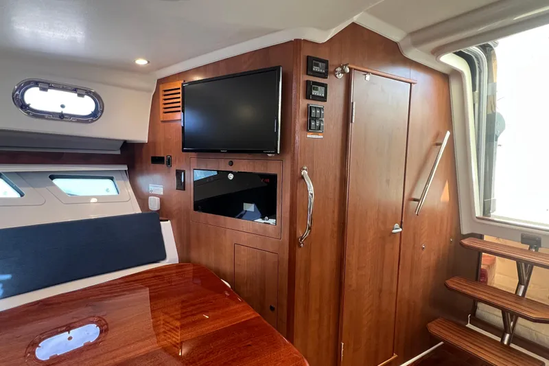Seaquel Yacht Photos Pics 2026 Pursuit OS 355 Offshore cabin interior with wood finish, TV, and stairs.