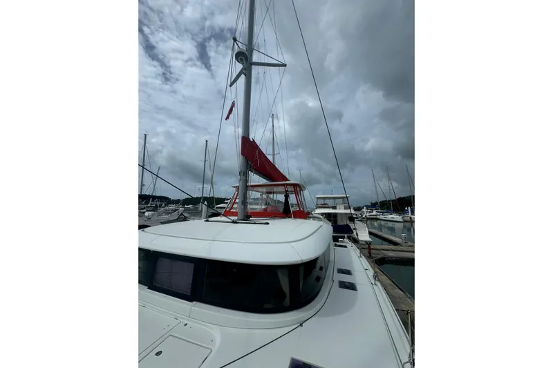Cc Princess Yacht Photos Pics 2020 Lagoon 46 catamaran docked under cloudy skies, featuring red sail accents.
