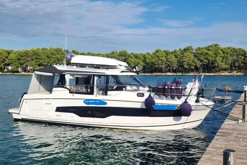  Yacht Photos Pics 2025 Jeanneau Merry Fisher 1095 yacht docked by a scenic shoreline.