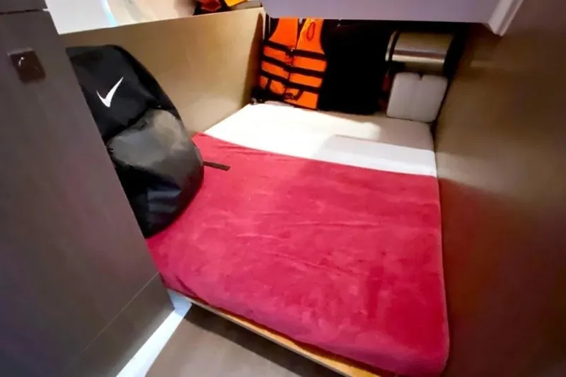  Yacht Photos Pics Cozy cabin interior of 2025 Jeanneau Merry Fisher 1095 with red bedding and storage.