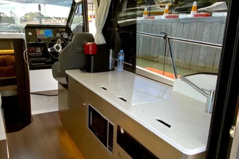  Yacht Photos Pics Interior of 2025 Jeanneau Merry Fisher 1095, featuring helm and modern kitchenette.