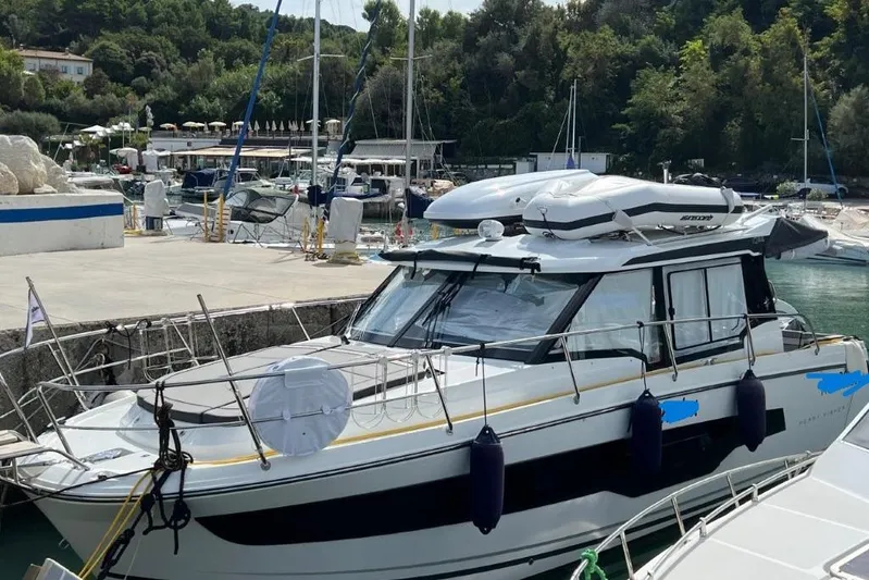  Yacht Photos Pics 2025 Jeanneau Merry Fisher 1095 docked at a marina, surrounded by lush greenery.