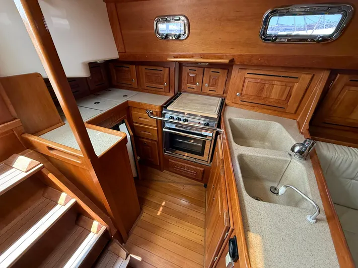 Chapter 9 Yacht Photos Pics Interior of 2012 Tartan 4000 yacht kitchen with wood cabinetry and dual sinks.